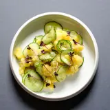 Ein köstlicher Kartoffelsalat mit frischen Gurkenscheiben, garniert mit zarten roten Sprossen und Dill.
