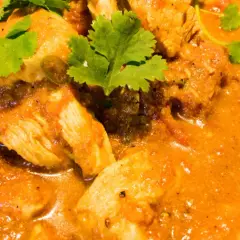 Ein köstliches indisches Curry Rezept mit zarten Hähnchenstücken in einer cremigen Tomaten-Currysauce, garniert mit frischem Koriander.