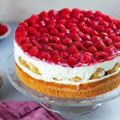 Eine köstliche Windbeuteltorte mit Himbeeren, geschichtet mit Sahne und Biskuit, verlockt zum Genuss.