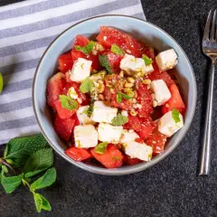 Erfrischender Wassermelonen Feta Salat mit Minze und Pinienkernen, garniert mit Limettenabrieb. Perfekt für heiße Tage!