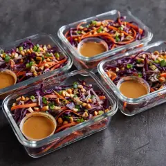 Vier Glasbehälter mit einem bunten Salat aus Rotkohl, Karotten und Erdnüssen. Perfekt für Rezepte mit viel Protein und wenig Kalorien.