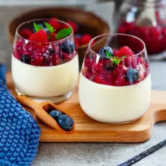Zwei Gläser Panna Cotta mit Beerenkompott, ein perfektes Beispiel für schnelle Desserts zum Vorbereiten.
