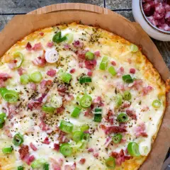 Leckerer low carb Flammkuchen mit Speck und Frühlingszwiebeln, goldbraun gebacken und bereit zum Genießen.