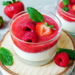 Zwei Gläser mit schnellen Desserts im Glas mit Joghurt, garniert mit frischen Beeren und Minze.