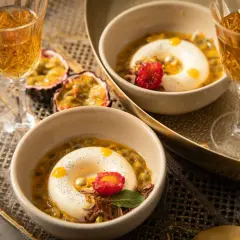 Zwei Panna Cotta-Desserts, inspiriert vom original italienischen Rezept, serviert mit Passionsfrucht und einem Hauch von Himbeere.