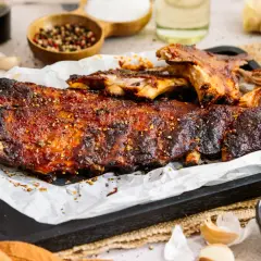 Saftige spareribs im backofen, glasiert und mit Gewürzen bestreut, serviert mit BBQ-Sauce.