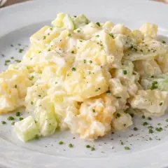 Cremiger Kartoffelsalat mit Sellerie und Schnittlauch, serviert auf einem weißen Teller. Ein köstlicher Klassiker, der an 7 Tassen Salat erinnert.