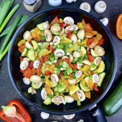 Buntes Gemüse in der Pfanne, perfekt für ein leichtes Abendessen mit wenig Kalorien. Zucchini, Paprika und Pilze werden mit Frühlingszwiebeln verfeinert.