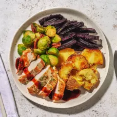 Ein Teller mit gebratenem Hähnchen, Rosenkohl, lila Karotten und Kartoffeln. Perfekt für alle, die **high carb rezepte** lieben und eine sättigende Mahlzeit suchen.