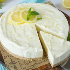 Cremige Philadelphia Torte mit Zitronenscheiben und Minze, ein Stück wurde bereits angeschnitten.
