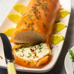 Eine köstliche Vorspeise mit Lachs: ein zarter Lachsrolle gefüllt mit einer cremigen Masse, garniert mit Dill und Zitrone.