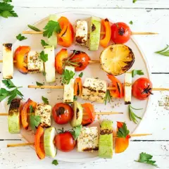 Gegrillte Spieße mit Halloumi, Paprika, Zucchini und Tomaten – köstliche vegetarische Gerichte, garniert mit frischer Petersilie und Rosmarin.