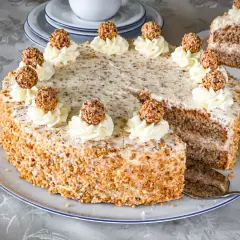Ein köstliches Giotto Torte Rezept: Eine runde Torte mit Nuss-Crunch, verziert mit Sahnetuffs und Giotto-Kugeln.