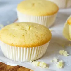 Frisch gebackene Vanille-Muffins, perfekt für ein einfaches Muffins Rezept. Einer ist angeschnitten und zeigt die saftige Krume.