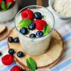 Erfrischendes Glas Overnight Oats mit Joghurt, garniert mit frischen Beeren und Minze. Perfekt für einen gesunden Start in den Tag.