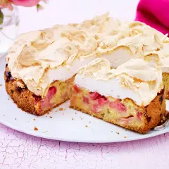 Ein saftiger Rhabarberkuchen mit einer luftigen Baiserhaube, auf einem weißen Teller angerichtet.