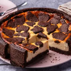 Ein saftiger russischer Zupfkuchen mit dunklem Schokoladenboden und cremiger Füllung, belegt mit zupfartigen Schokoladenstücken.
