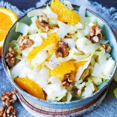 Erfrischender chicoree salat mit saftigen Orangenspalten und knackigen Walnüssen, garniert mit Pfeffer.
