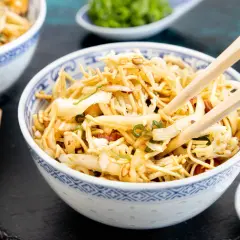 Ein Schüsselchen "friss dich dumm Salat" mit Nudeln, Gemüse und Mandeln, bereit zum Genießen mit Stäbchen.