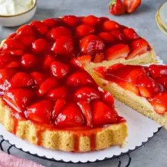 Ein saftiger Kuchen mit Erdbeeren, bedeckt mit glänzendem Tortenguss. Ein Stück wurde bereits entnommen, um die cremige Füllung zu enthüllen.