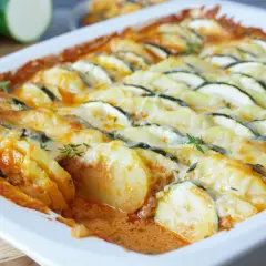 Herzhafter zucchini hackfleisch auflauf mit Kartoffeln und Käse überbacken, garniert mit frischen Kräutern.