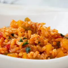 Eine köstliche Paprika Reis Pfanne mit roten und gelben Paprikastücken, serviert in einer weißen Schüssel.