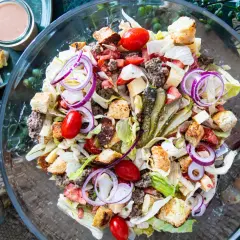 Ein üppiger Big Mac Salat mit Hackfleisch, Salat, Tomaten, Zwiebeln, Gurken und Croutons in einer Glasschüssel.