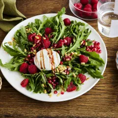 Ein frischer Salat mit Rucola, Himbeeren, Granatapfelkernen und Pinienkernen, gekrönt von cremiger Burrata. Perfekt für leichte Burrata Rezepte.