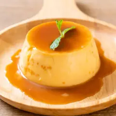 Cremiger Karamellpudding, perfekt zum Pudding selber machen. Mit Minze garniert auf einem Holztablett.