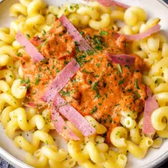 Gedrehte Nudeln mit cremiger Tomatensoße und rosa Schinkenstreifen, ein Beispiel für schnelle Pasta Rezepte.