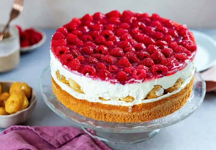 Eine köstliche Windbeuteltorte mit Himbeeren, geschichtet mit Sahne und Biskuit, verlockt zum Genuss.
