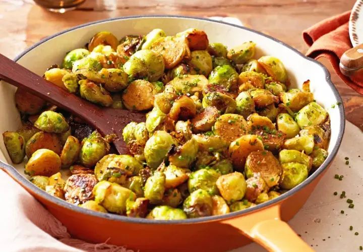 Leckere Rosenkohl Rezepte Pfanne mit gebratenem Rosenkohl, Kartoffeln und Kräutern in einer Gusseisenpfanne.