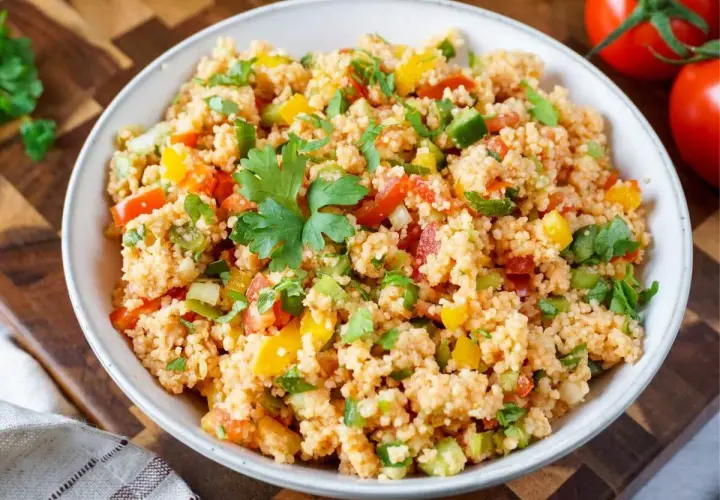 Frischer Couscous-Salat mit Tomaten, Paprika und Kräutern, garniert mit Petersilie. Ein leichter und gesunder Genuss.