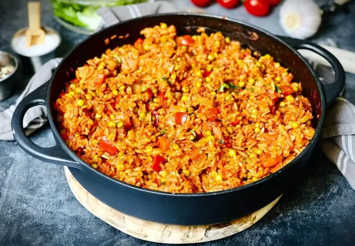 Herzhafter Djuvec Reis mit Mais und Paprika, serviert in einer Gusseisenpfanne. Ein köstliches Gericht, das nach mehr schmeckt.