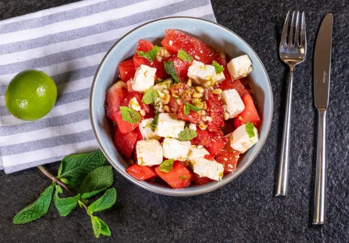 Erfrischender Wassermelonen Feta Salat mit Minze und Pinienkernen, garniert mit Limettenabrieb. Perfekt für heiße Tage!