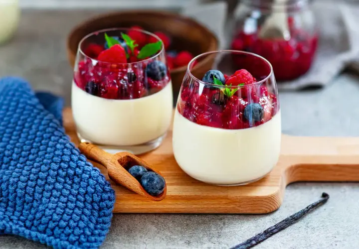 Zwei Gläser Panna Cotta mit Beerenkompott, ein perfektes Beispiel für schnelle Desserts zum Vorbereiten.