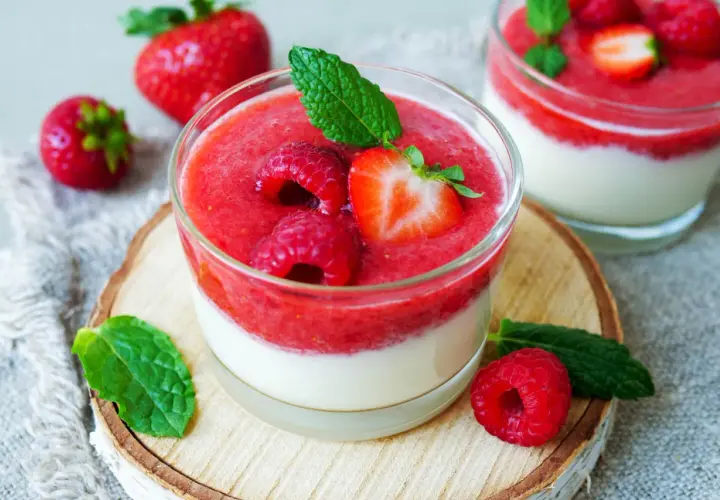 Zwei Gläser mit schnellen Desserts im Glas mit Joghurt, garniert mit frischen Beeren und Minze.
