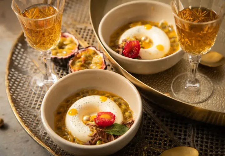 Zwei Panna Cotta-Desserts, inspiriert vom original italienischen Rezept, serviert mit Passionsfrucht und einem Hauch von Himbeere.
