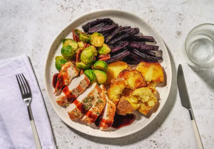 Ein Teller mit gebratenem Hähnchen, Rosenkohl, lila Karotten und Kartoffeln. Perfekt für alle, die **high carb rezepte** lieben und eine sättigende Mahlzeit suchen.
