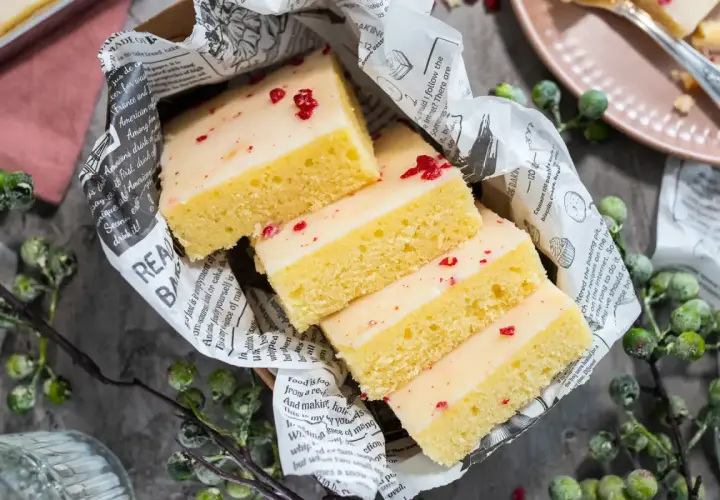 Saftige Kuchenstücke mit weißer Glasur und roten Streuseln, inspiriert von einem Tassenkuchen Rezept Blech.