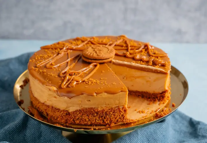Ein köstlicher Lotus Cheesecake mit Karamellglasur und zerbröselten Keksen, dekoriert mit einem ganzen Keks.