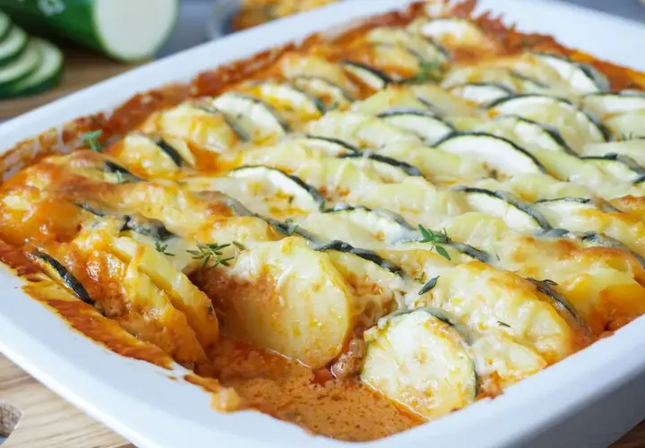 Herzhafter zucchini hackfleisch auflauf mit Kartoffeln und Käse überbacken, garniert mit frischen Kräutern.