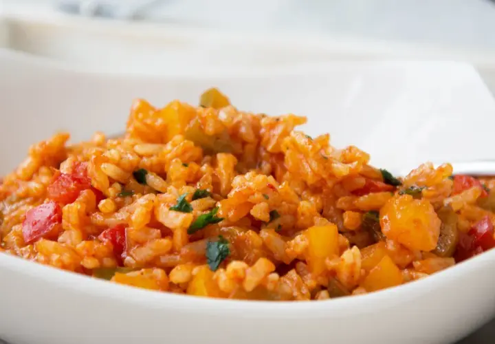 Eine köstliche Paprika Reis Pfanne mit roten und gelben Paprikastücken, serviert in einer weißen Schüssel.