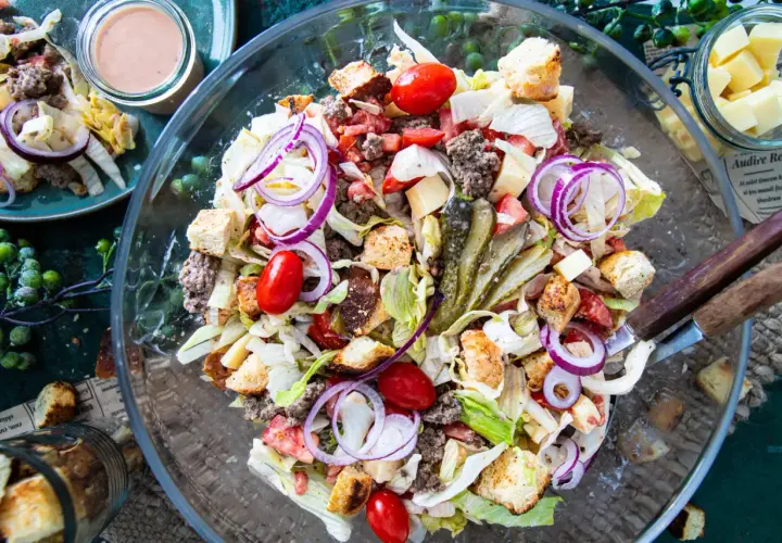 Ein üppiger Big Mac Salat mit Hackfleisch, Salat, Tomaten, Zwiebeln, Gurken und Croutons in einer Glasschüssel.