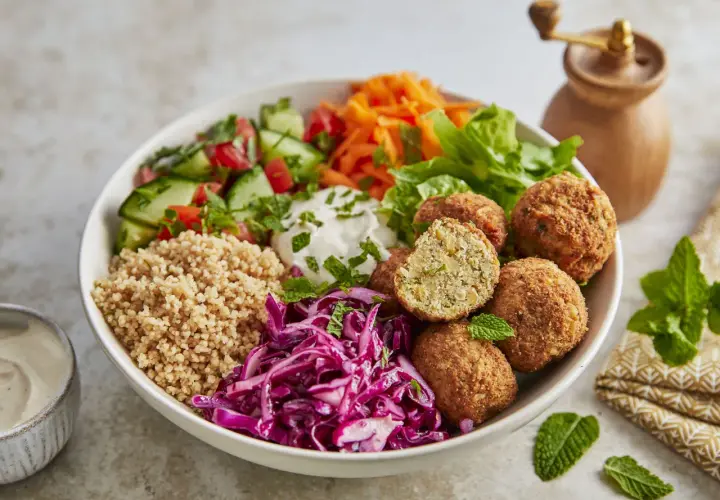 Schüssel mit Falafel, Couscous, Tomaten, Gurken, Rotkohl und Joghurt. Perfekt für gesunde Essen Rezepte.