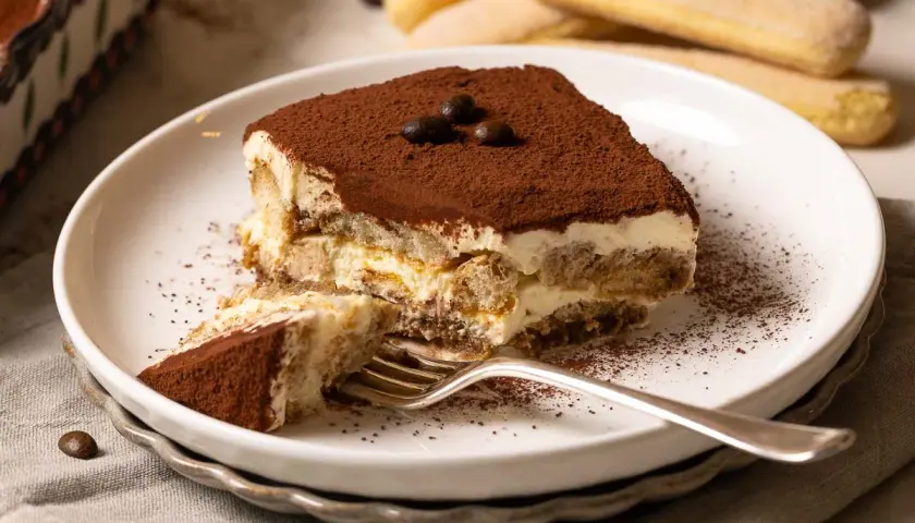 Ein Stück cremiges Tiramisu, das nach einem authentischen tiramisu rezept original italienisch schmeckt. Mit Löffelbiskuits, Mascarpone und Kakao.
