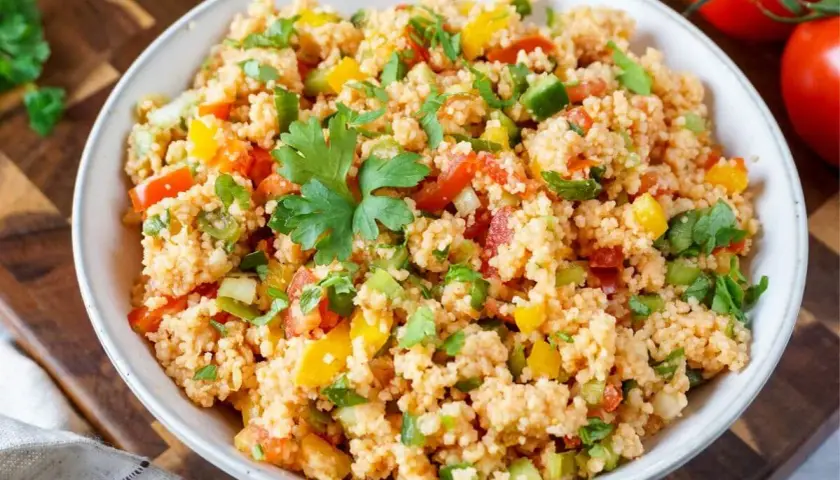 Frischer Couscous-Salat mit Tomaten, Paprika und Kräutern, garniert mit Petersilie. Ein leichter und gesunder Genuss.