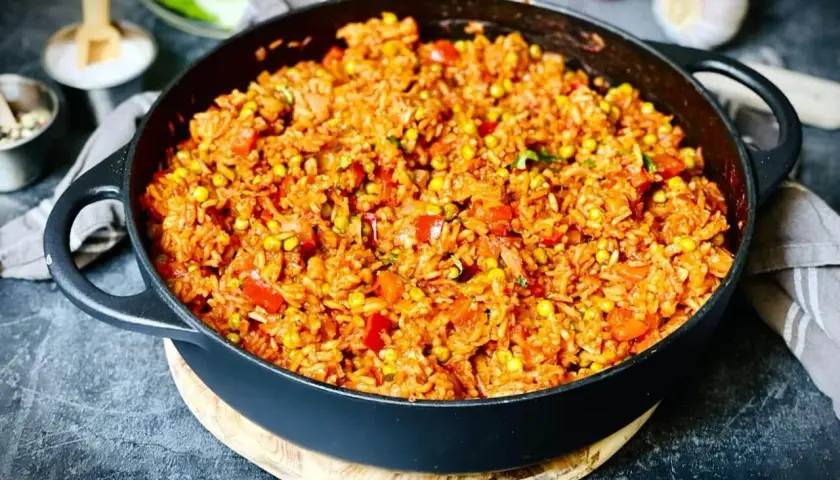 Herzhafter Djuvec Reis mit Mais und Paprika, serviert in einer Gusseisenpfanne. Ein köstliches Gericht, das nach mehr schmeckt.