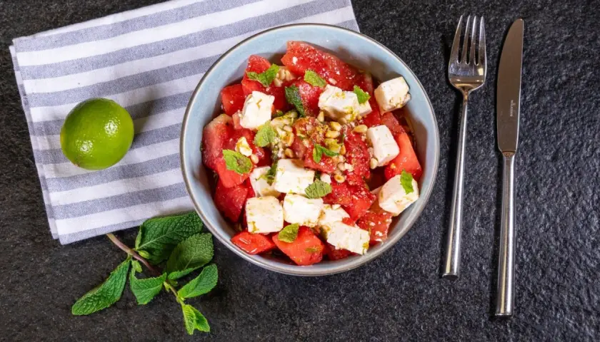 Erfrischender Wassermelonen Feta Salat mit Minze und Pinienkernen, garniert mit Limettenabrieb. Perfekt für heiße Tage!