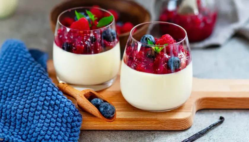 Zwei Gläser Panna Cotta mit Beerenkompott, ein perfektes Beispiel für schnelle Desserts zum Vorbereiten.